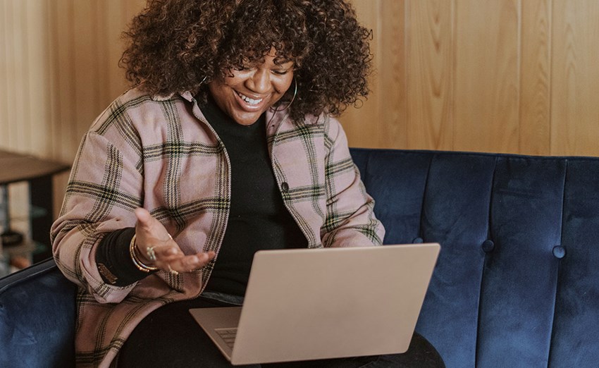 Woman sitting on a sofa working and having a conversation through a laptop